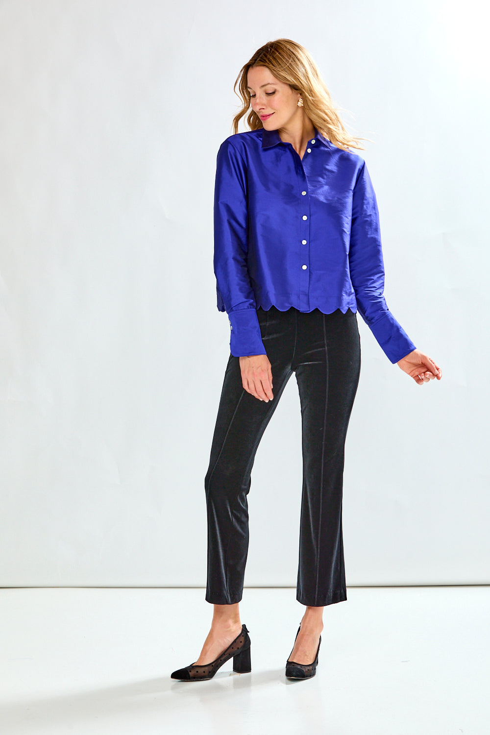 Woman wearing a blue blouse and black pants on a white background