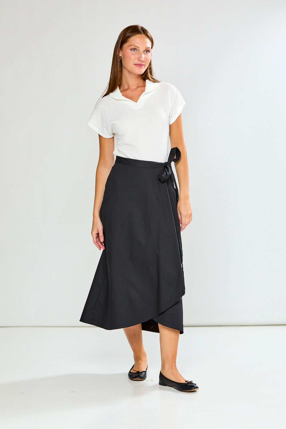 Woman wearing a white top and black skirt on a white background