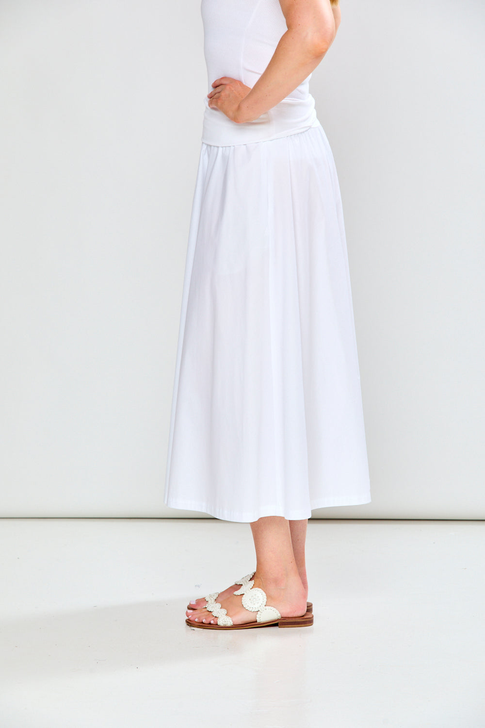 Person wearing a white dress and sandals on a plain background