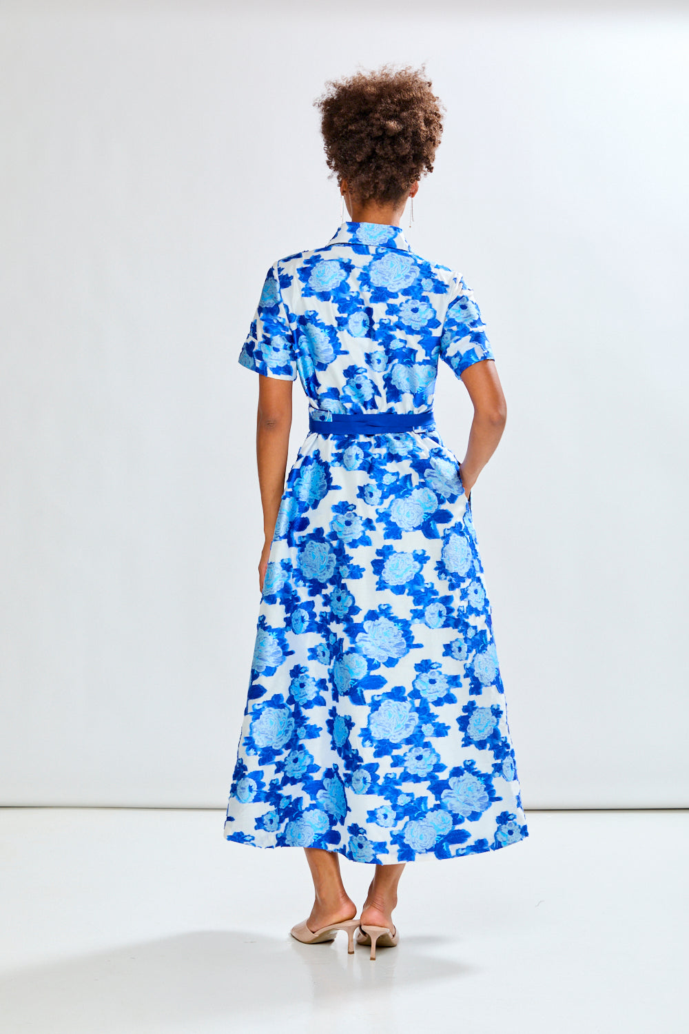 Woman wearing a blue floral dress against a white background
