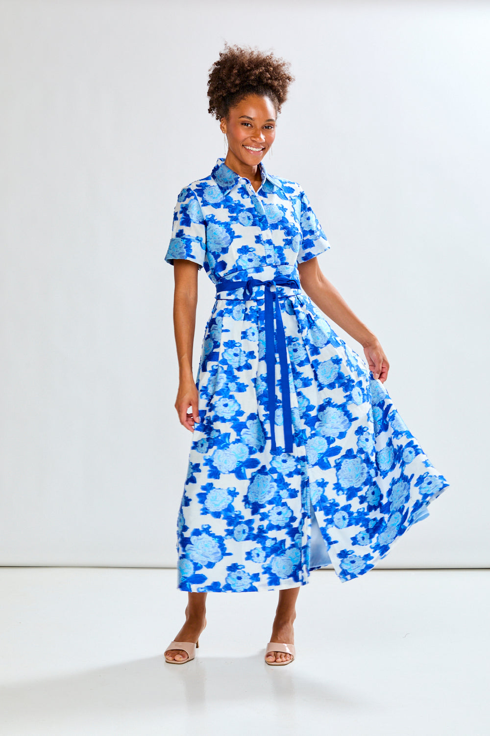 Woman wearing a blue floral dress against a white background