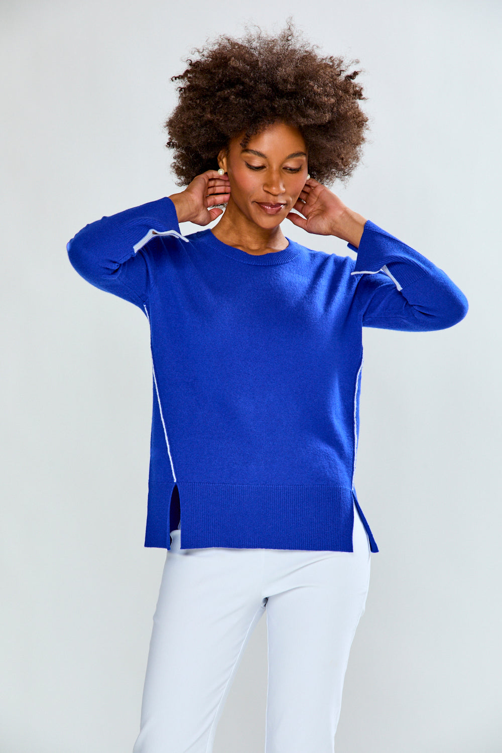 Woman wearing a blue sweater with white accents on a plain background