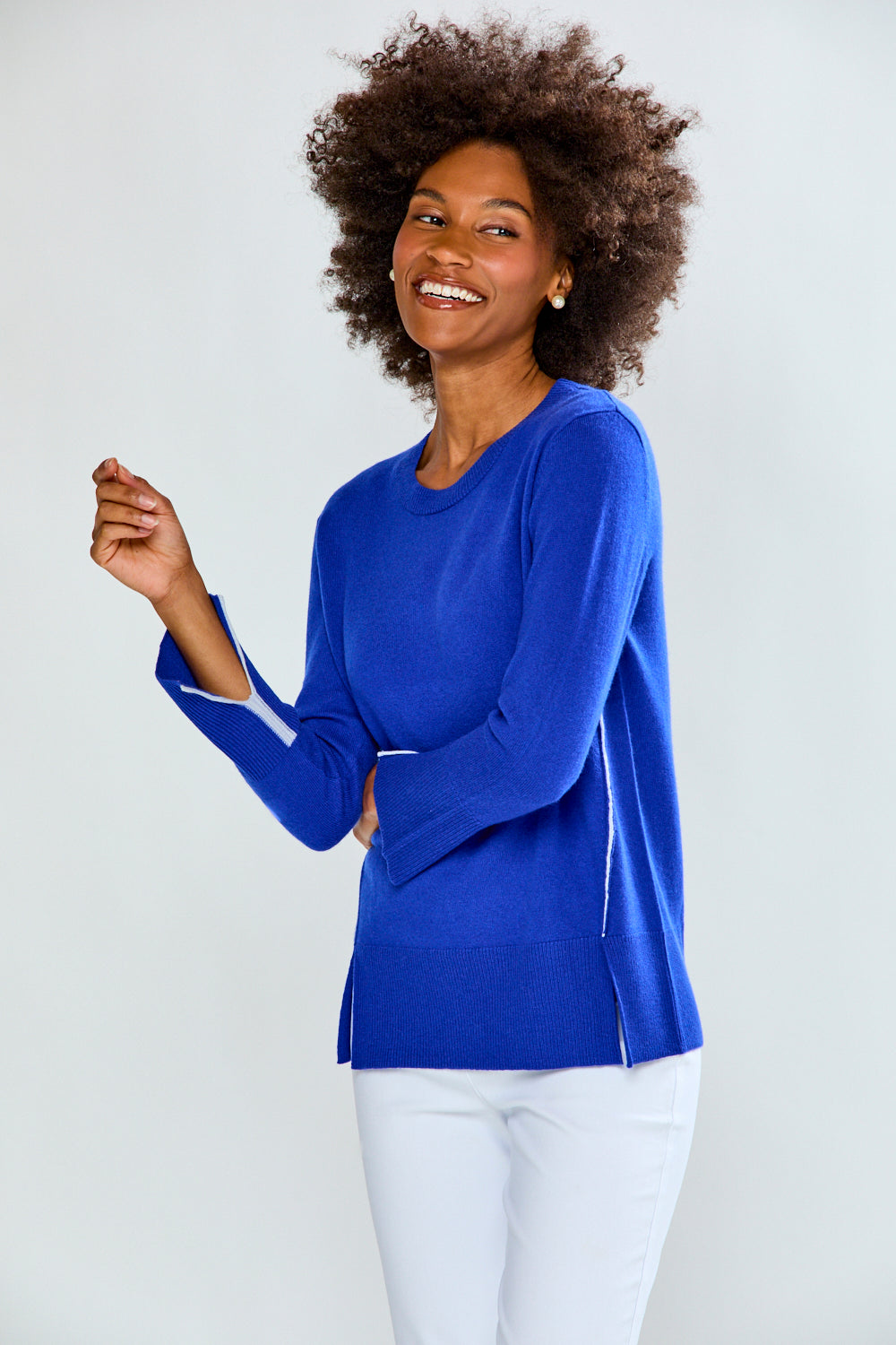 Woman wearing a blue sweater with white trim on a plain background