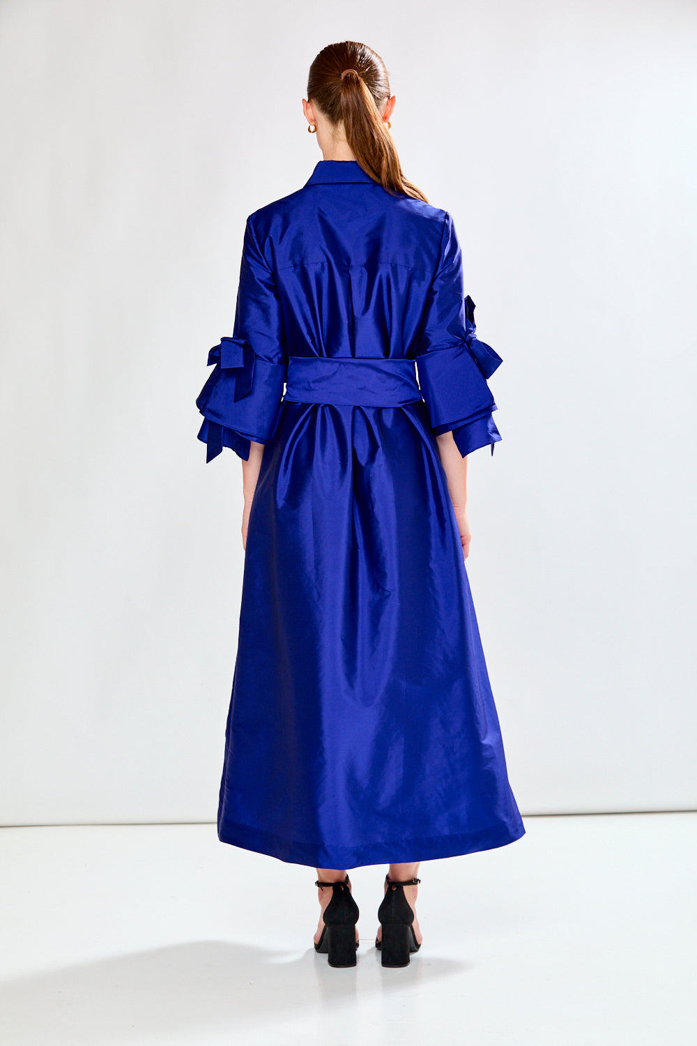 Woman wearing a blue dress with a large bow on a white background