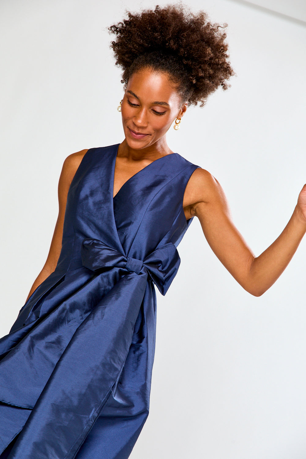Woman wearing a blue dress with a knot detail on a white background