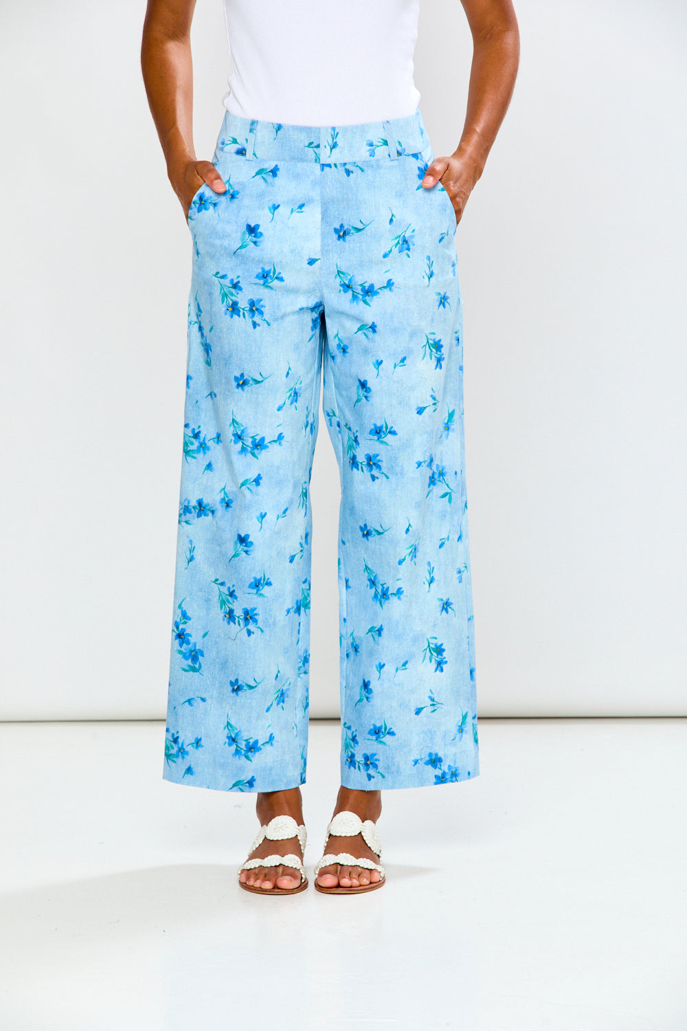 Person wearing light blue floral pants with a white background