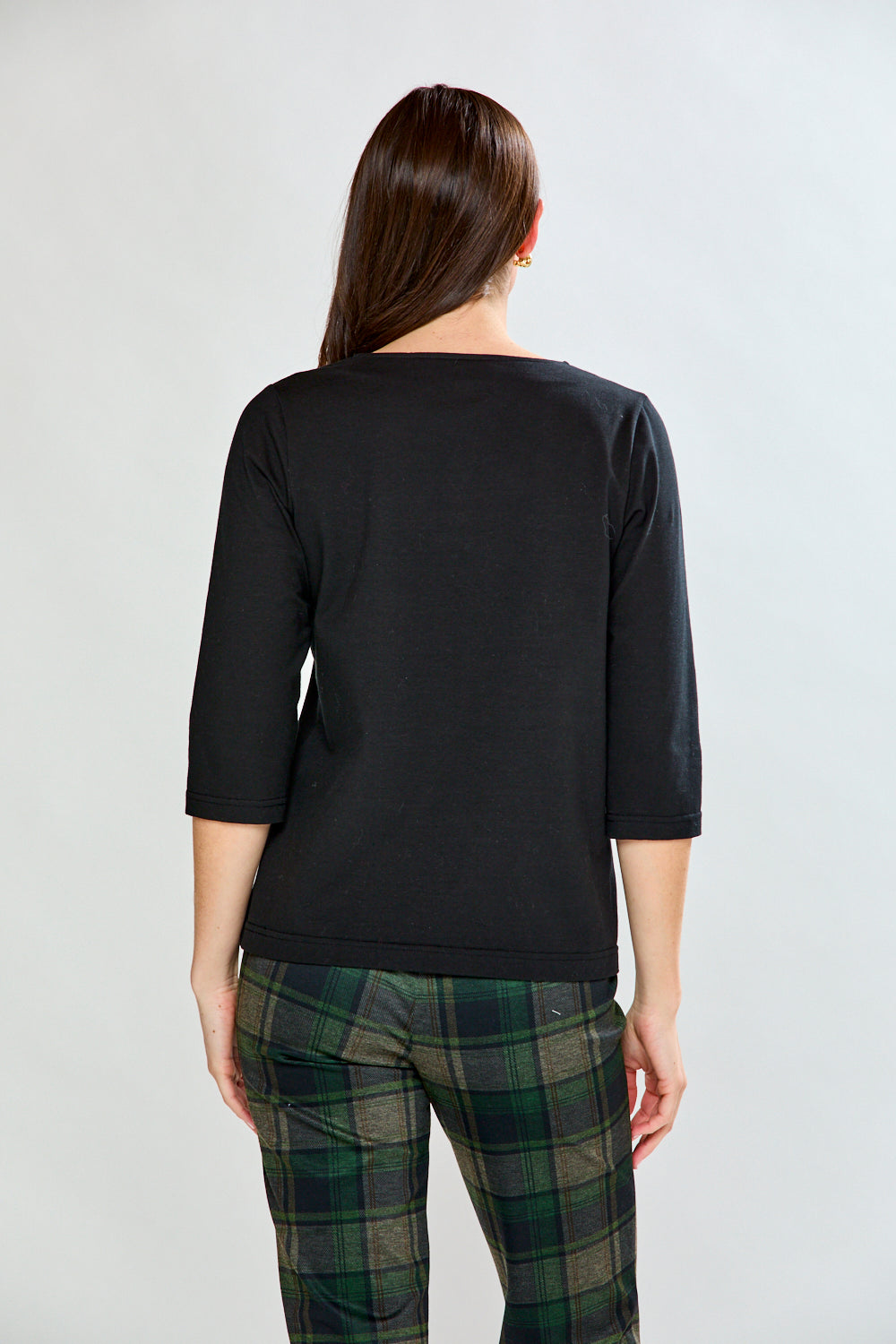 Woman wearing a black top and plaid pants on a white background