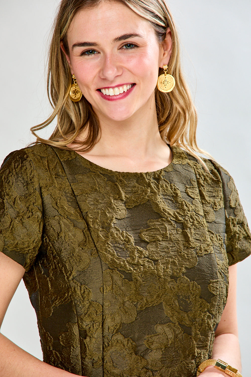 Woman wearing a green dress with a subtle pattern on a white background