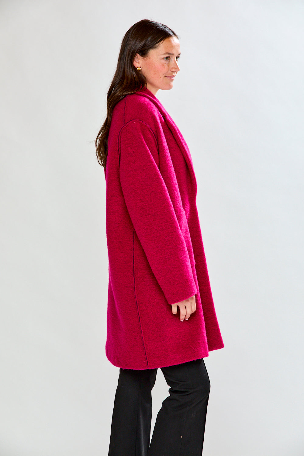 Woman wearing a bright pink coat against a white background