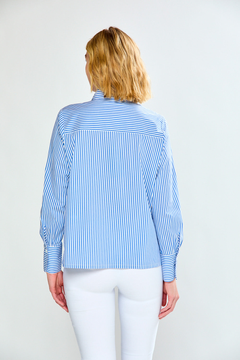 Woman wearing a blue and white striped shirt on a plain background