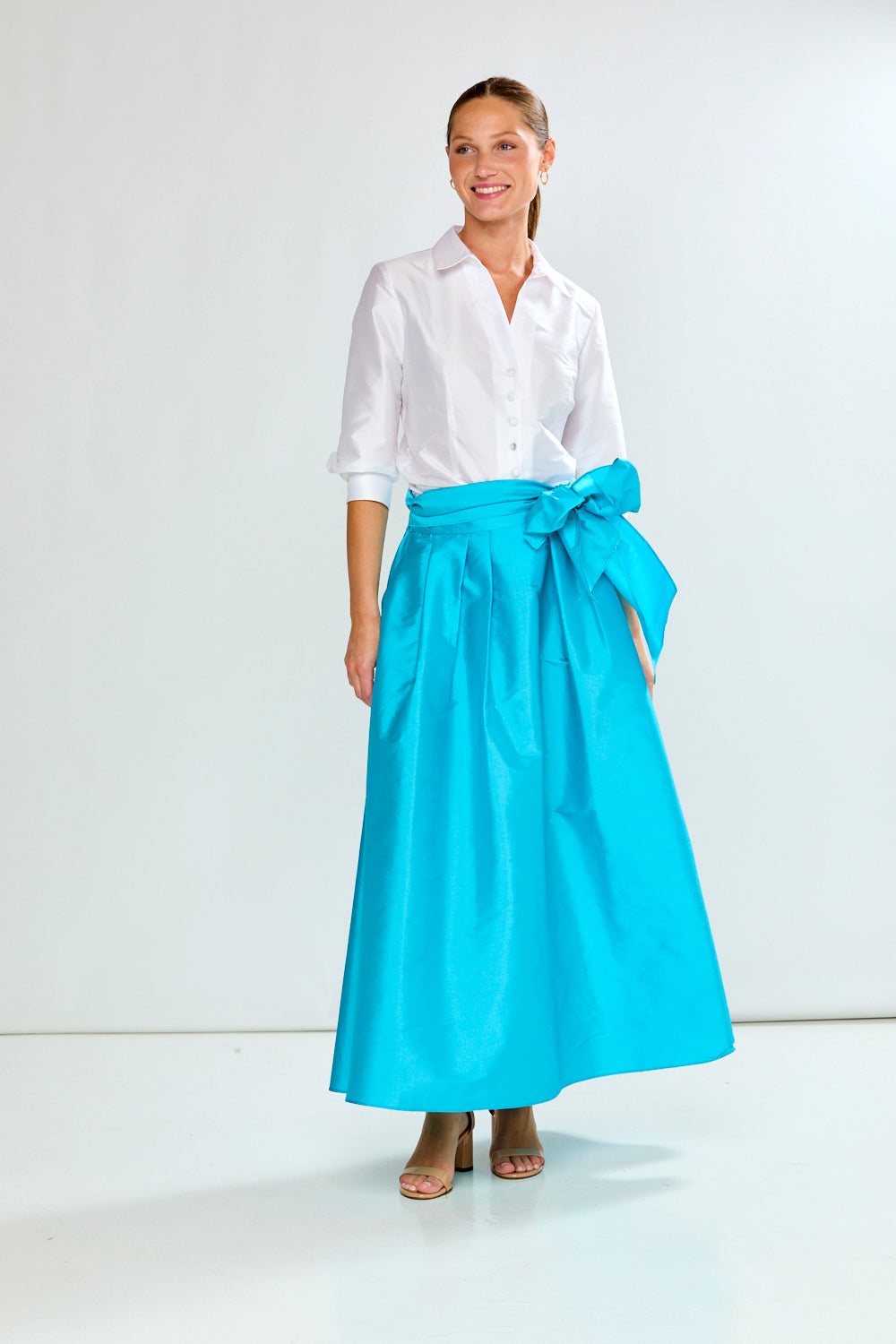 Woman wearing a white shirt and blue skirt on a white background