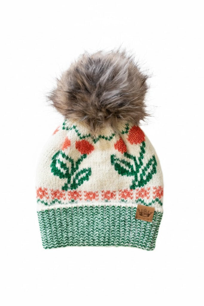 Knitted beanie with floral pattern and fur pom-pom on a white background