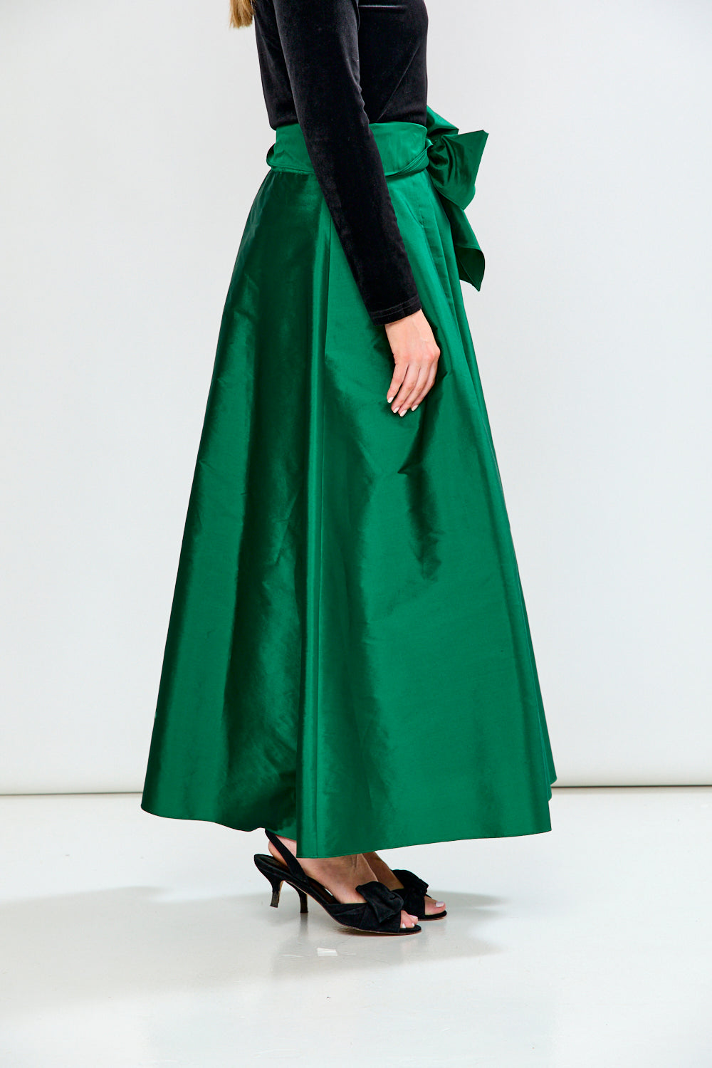 Woman wearing a Black top and Emerald skirt on a white background