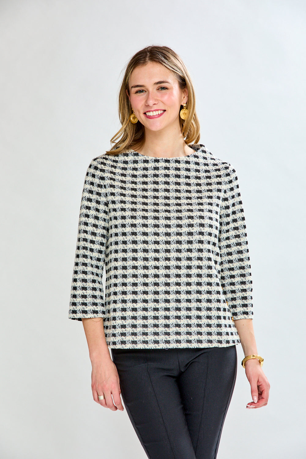 Woman wearing a black and white checkered blouse against a plain background
