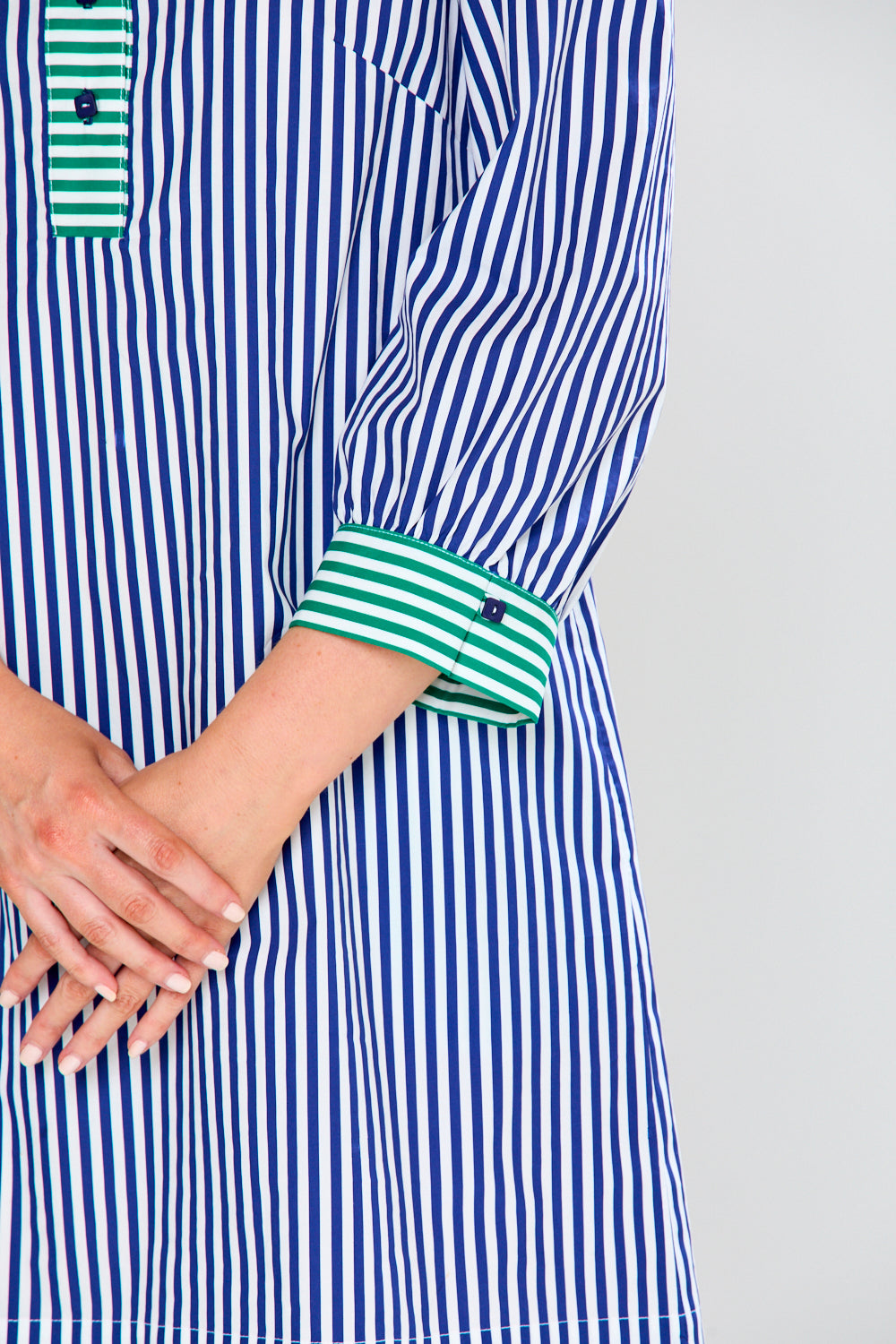 Blue and white striped shirt with green accents on a plain background