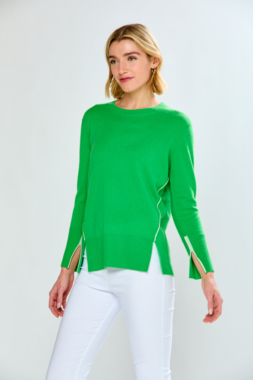 Woman wearing a green sweater with cut-out sleeves on a white background