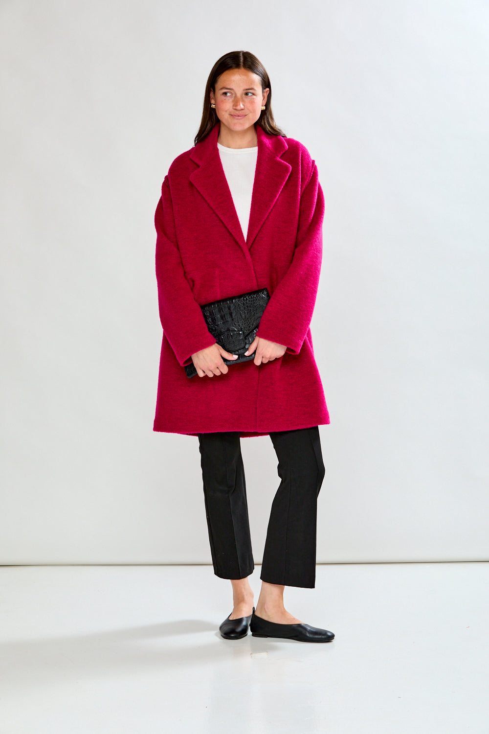 Woman wearing a bright pink coat against a white background