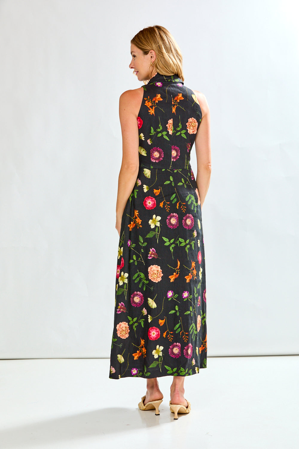 Woman wearing a black linen dress with multi colored flowers on it