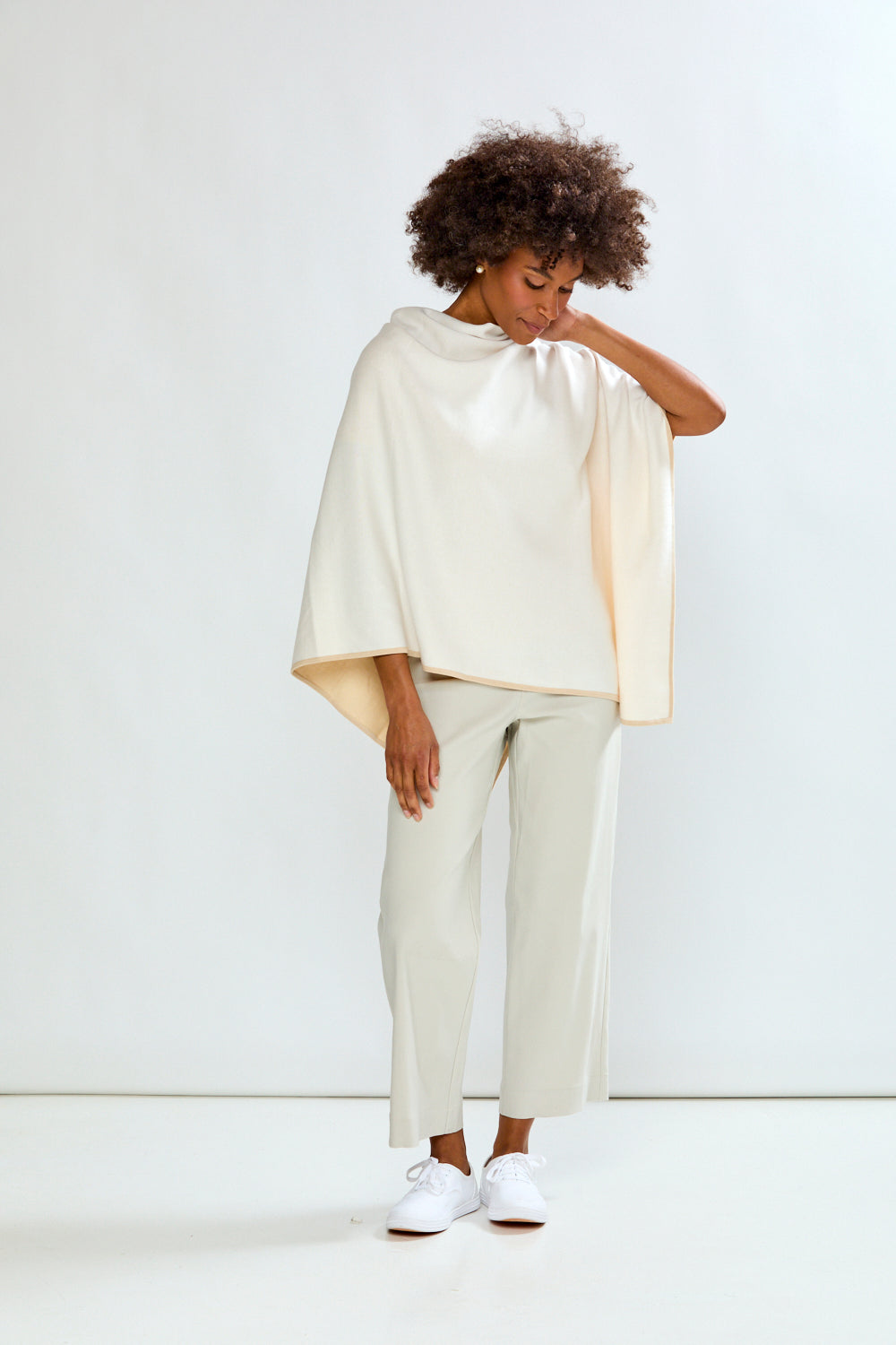 Person wearing a white cape and pants on a white background