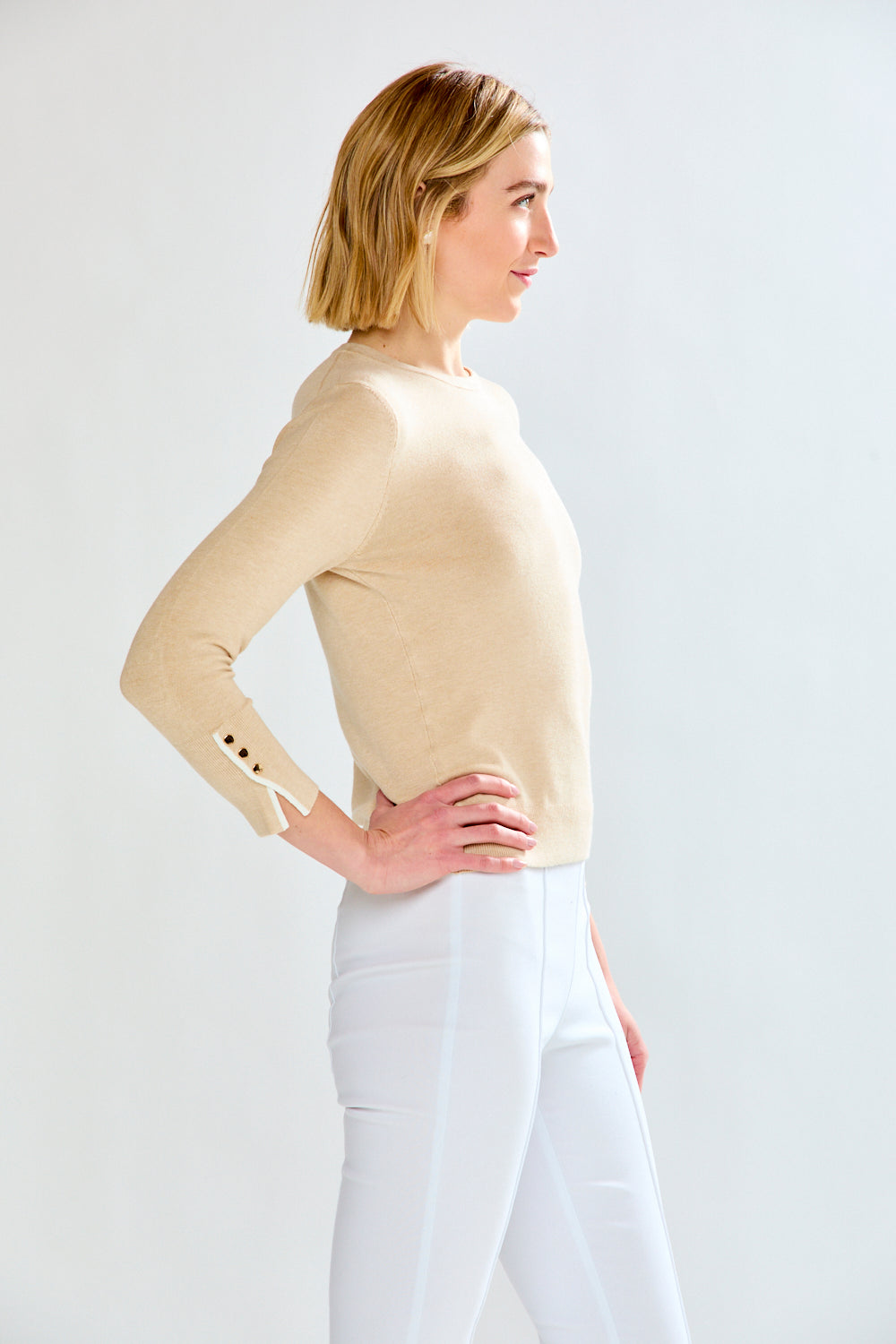 woman in tan sweater and white pants