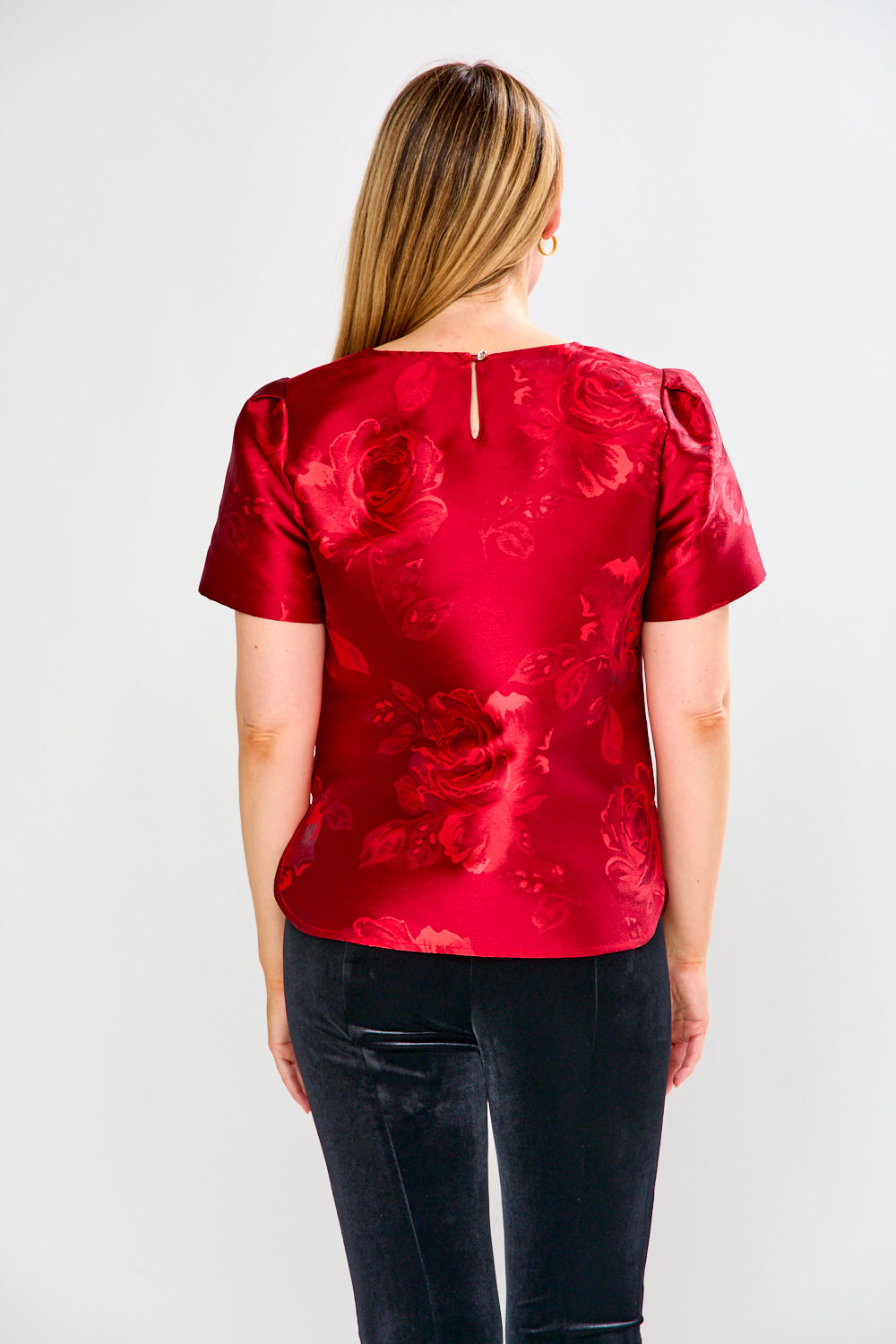 Woman wearing a red floral blouse with black pants on a white background