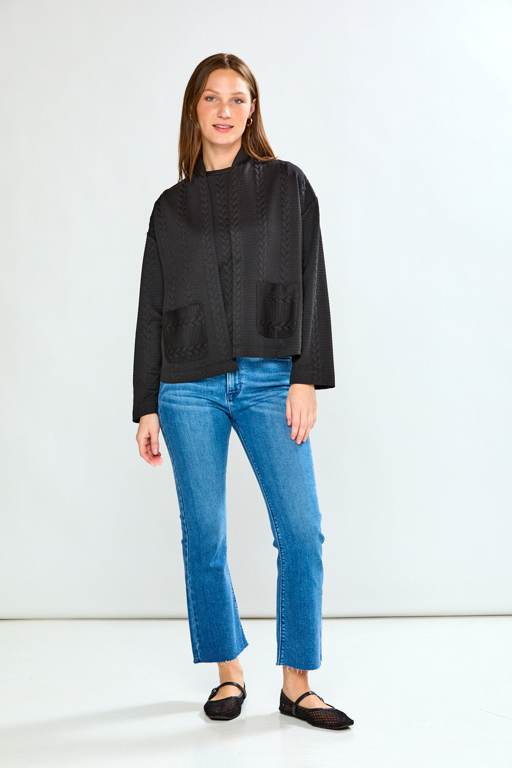 Woman wearing a black jacket and blue jeans on a white background