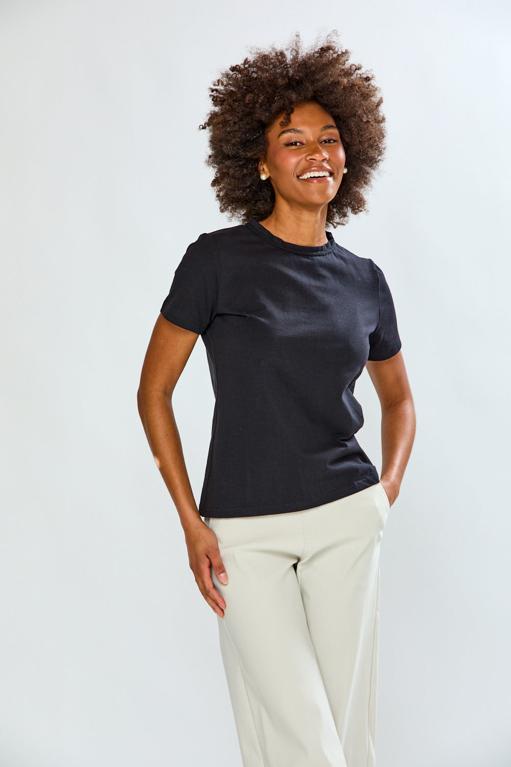 Woman wearing a black t-shirt and white pants against a plain background