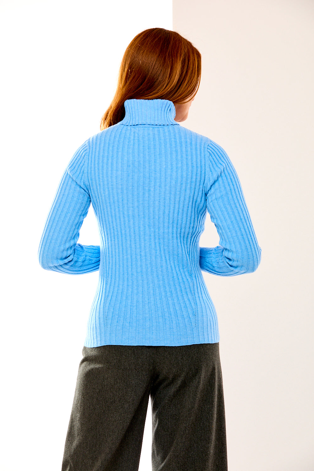 Person wearing a light blue ribbed sweater against a white background