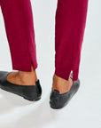 Person wearing raisin pants and black shoes on a white background