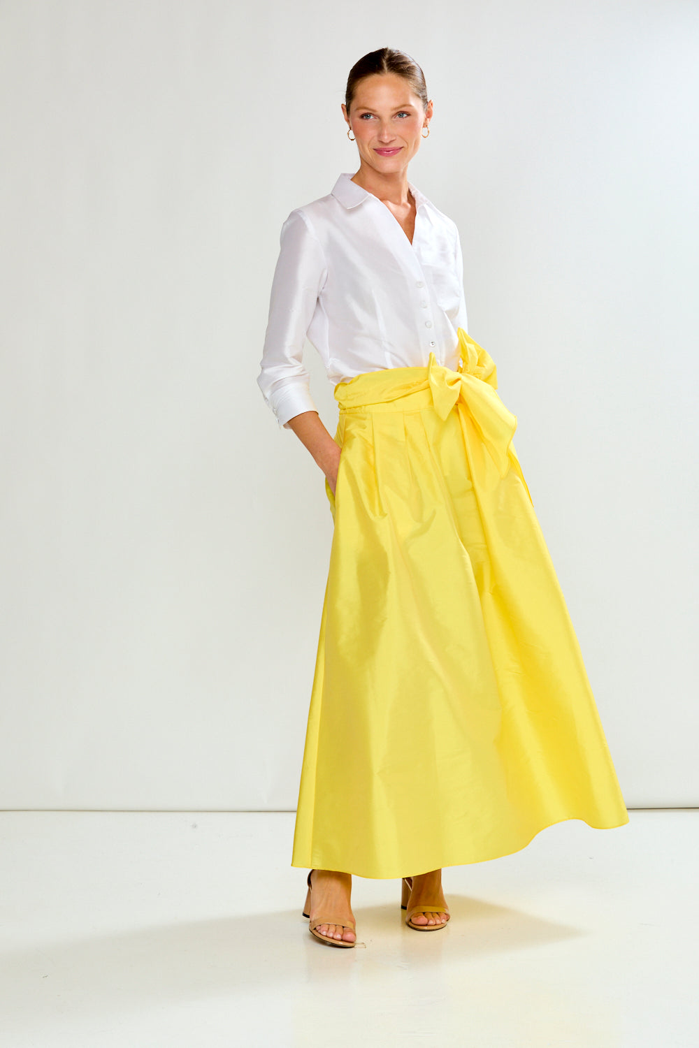 Woman wearing a white shirt and yellow skirt on a white background