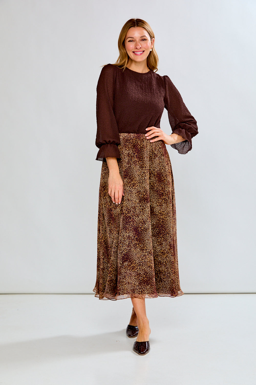 Woman wearing a brown blouse and patterned skirt on a white background