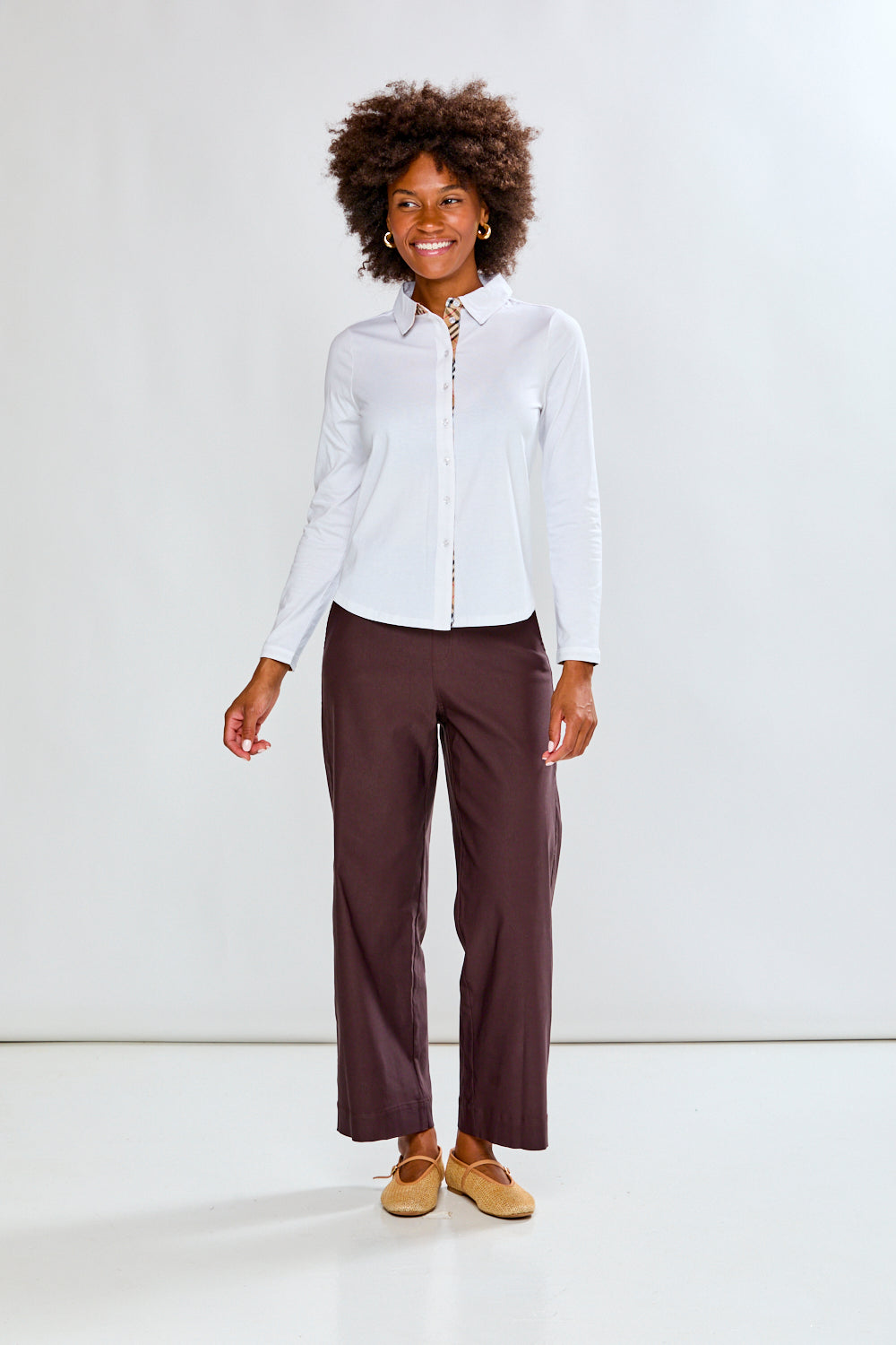 Woman wearing a white shirt and brown pants on a white background