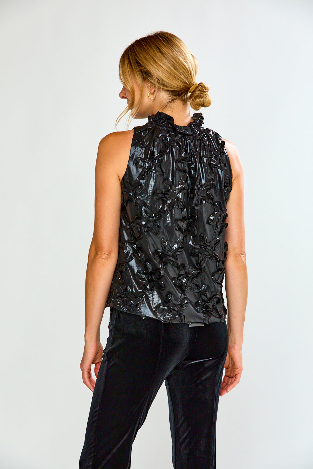 Woman wearing a black metallic top and black pants on a white background