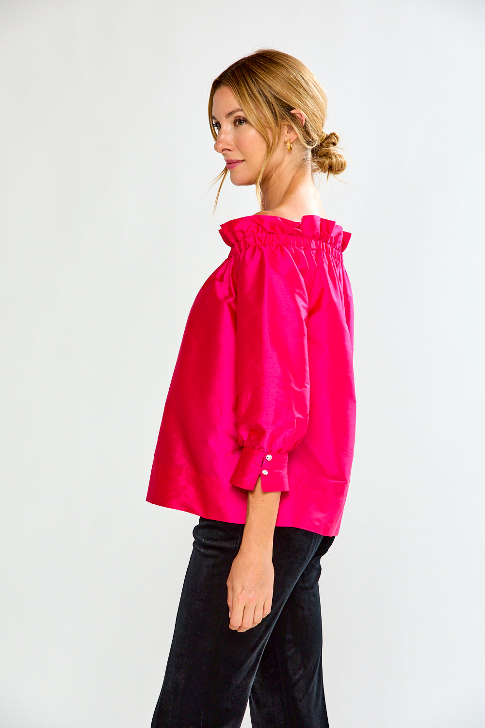 Woman wearing a bright pink off-shoulder top against a white background