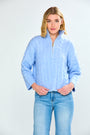 Woman wearing a denim cable knit sweater and blue jeans on a white background
