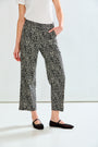 A model wearing black and white patterned cropped trousers, paired with a white ribbed top and black flat shoes, standing against a white studio background.