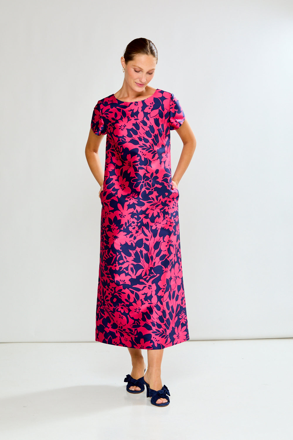 Woman wearing a pink and navy floral dress on a white background