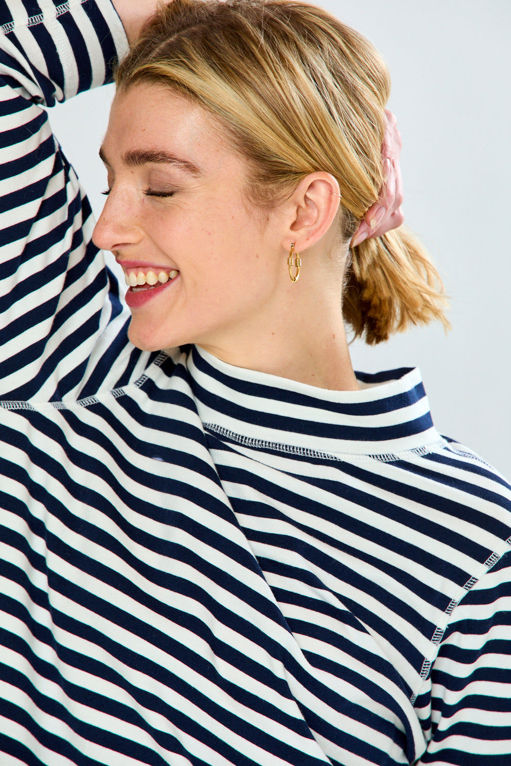 Two people wearing navy and white striped shirts against a light background