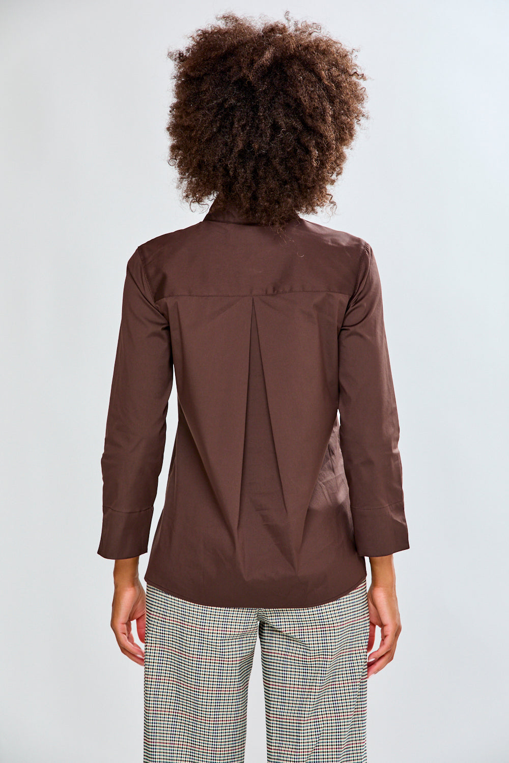 Woman wearing a chocolate shirt and plaid pants on a white background
