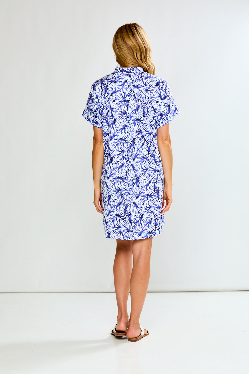 Woman wearing a blue and white floral dress against a white background
