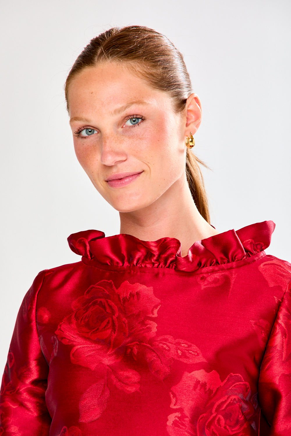 Woman wearing a red dress with floral pattern on a white background