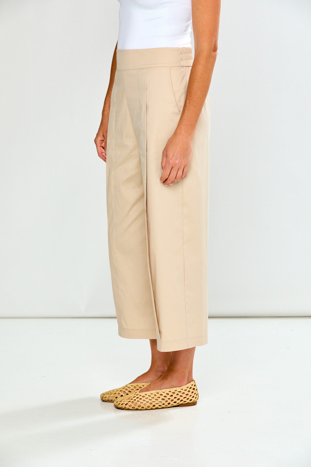 Woman wearing sand wide-leg pants on a white background