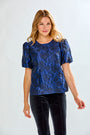 Woman wearing a blue floral blouse with puff sleeves against a white background