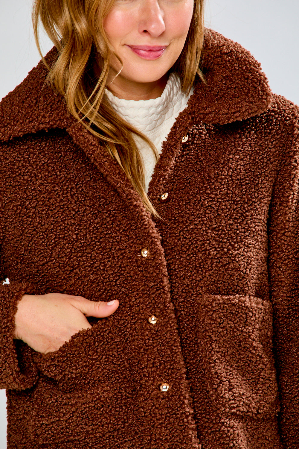 Brown teddy coat worn by a person with a neutral background