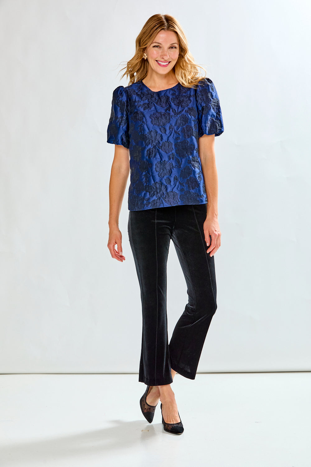 Woman wearing a blue floral blouse with puff sleeves against a white background