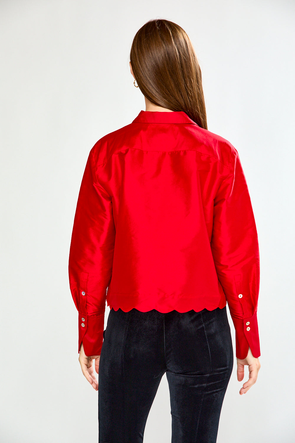 Woman wearing a red blouse and black pants on a white background