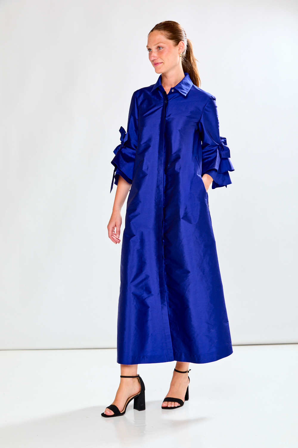 Woman wearing a blue taffeta dress in front of a white background