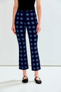 A model is shown from the waist down wearing navy blue cropped pants with a blue checkered pattern, paired with a black top and black flats.