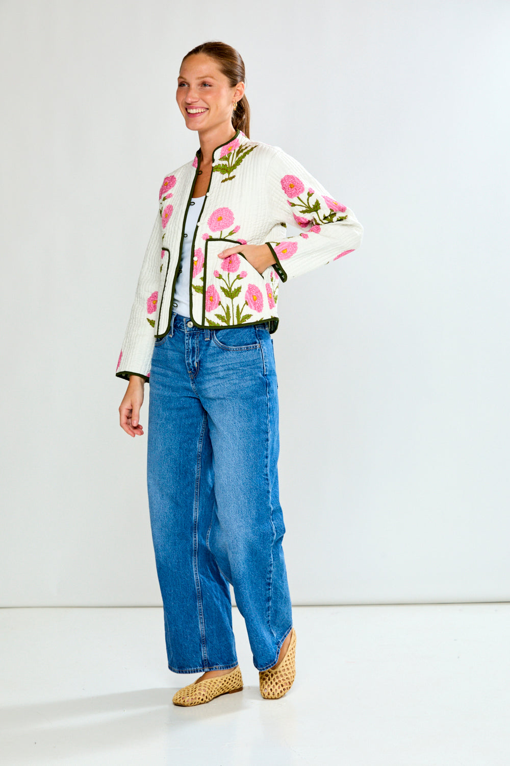 Woman wearing a floral jacket and blue jeans on a white background