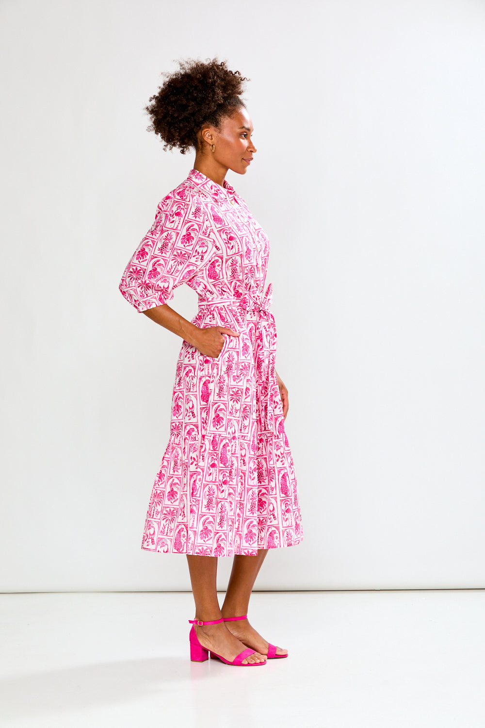 Woman wearing a pink and white patterned dress on a white background